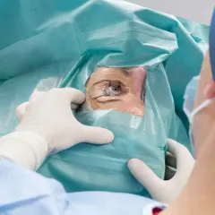 Oko pacjenta przygotowywane do zabiegu korekty laserowej wzroku. Chirurg w rękawiczkach precyzyjnie odsłania oko.