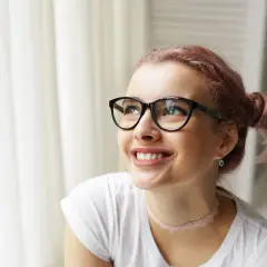 Uśmiechnięta dziewczyna w okularach, z różowymi włosami spiętymi w dwa kucyki. Jej spojrzenie kieruje się w górę, jakby zastanawiała się, co to jest luteina i jak może jej pomóc.