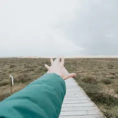 Ręka wyciągnięta w kierunku ścieżki przez pusty krajobraz, symbolizująca **widzenie tunelowe psychologia** i dążenie do celu.