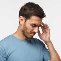 Mężczyzna z bólem głowy trzymający się za skroń.