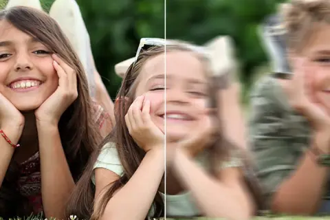 Dwie dziewczynki leżą na trawie. Lewa strona obrazu jest ostra, prawa rozmazana.