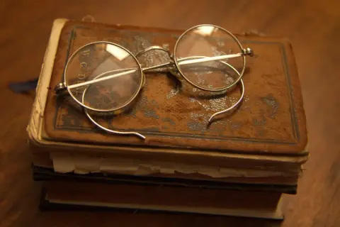 Stare okulary na zabytkowej księdze, jakbyśmy cofali się do czasów, kiedy wynaleziono okulary, by czytać starodruki.