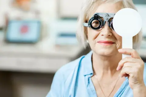 Starsza kobieta z soczewkami próbnymi na oczach, badanie wzroku w celu diagnozy zaburzeń widzenia ICD 10.