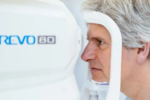Mężczyzna poddaje się badaniu tomografia oka na nowoczesnym urządzeniu REVO 80.