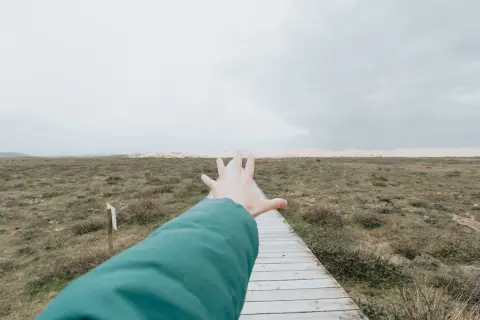 Ręka wyciągnięta w kierunku ścieżki przez pusty krajobraz, symbolizująca **widzenie tunelowe psychologia** i dążenie do celu.