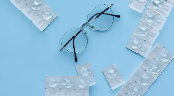 Okulary i opakowania soczewek kontaktowych. Soczewki kontaktowe, podobnie jak soczewki okularowe, mają zdolność skupiającą.