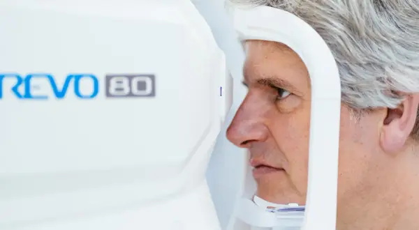Mężczyzna poddaje się badaniu tomografia oka na nowoczesnym urządzeniu REVO 80.