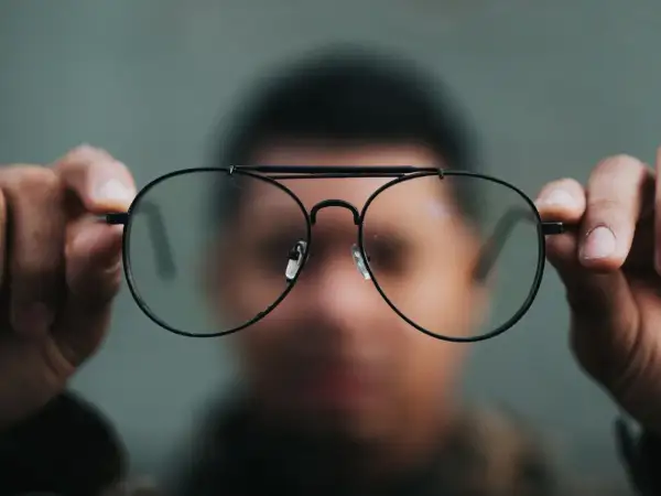 Osoba trzyma okulary, które mogą pomóc w przypadku niedowidzenia na jedno oko, co może być podstawą do ubiegania się o rentę.