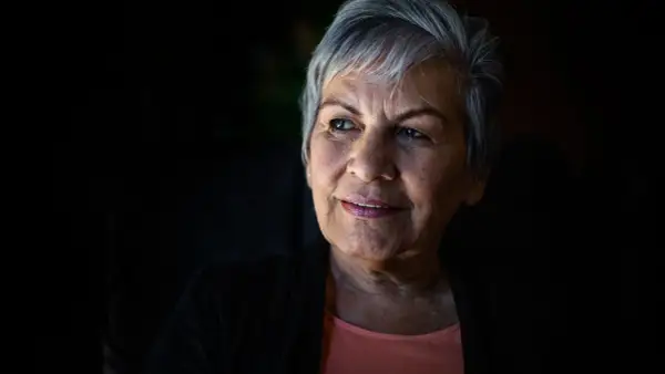 Portret starszej kobiety z siwymi włosami, patrzącej w bok z lekkim uśmiechem.