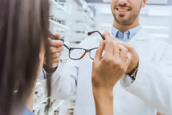 Optometrysta pokazuje okulary klientce. Dowiedz się, ile wynosi dofinansowanie do okularów przez pracodawcę.